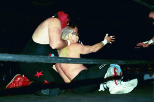Masked Superstar applies rear chin lock to Ricky Morton